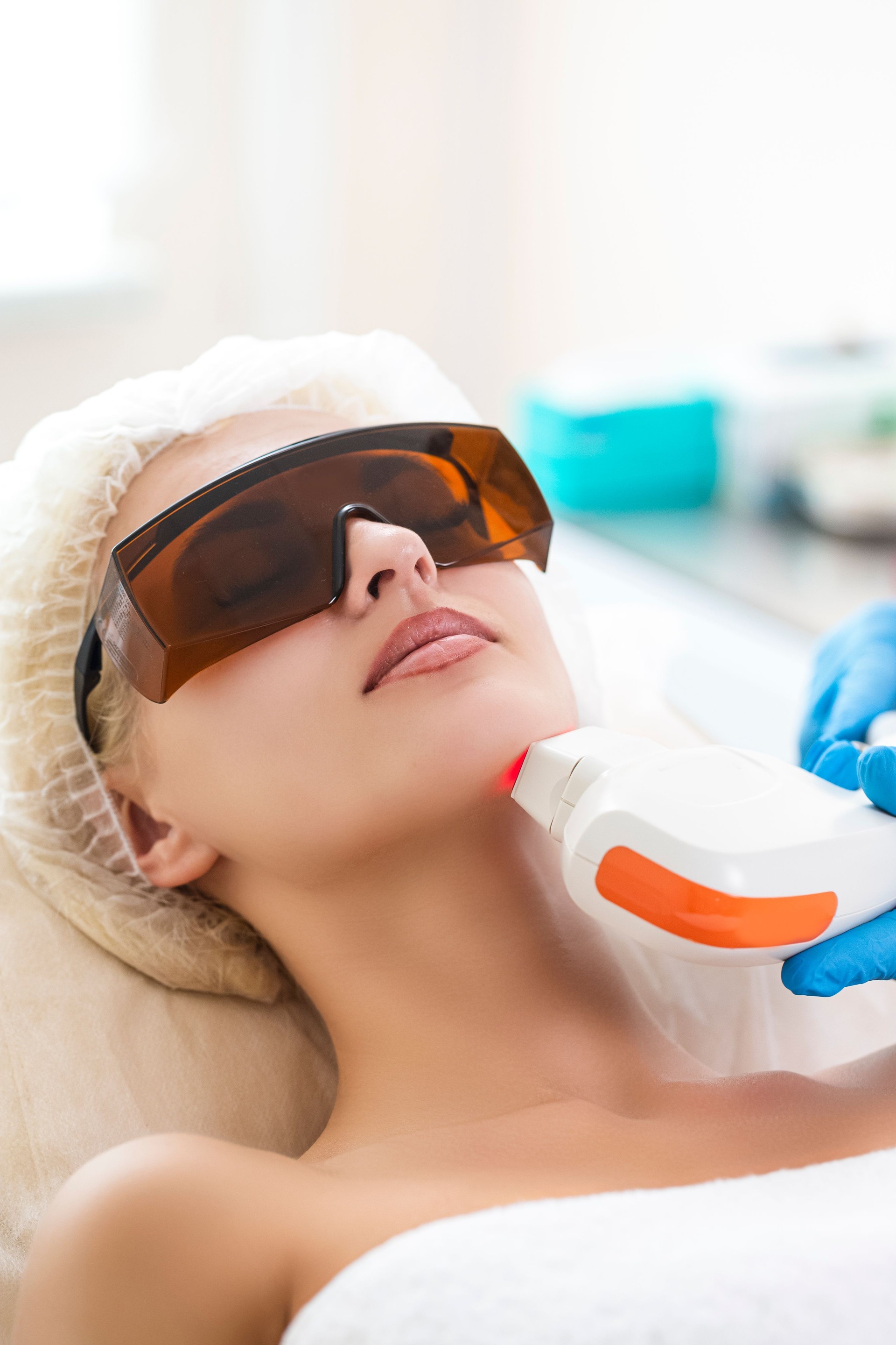 Young Caucasian Winsome Woman Getting IPL Laser and Ultrasound Facial Treatment in Modern Medical Spa Center As Skin Rejuvenation Concept